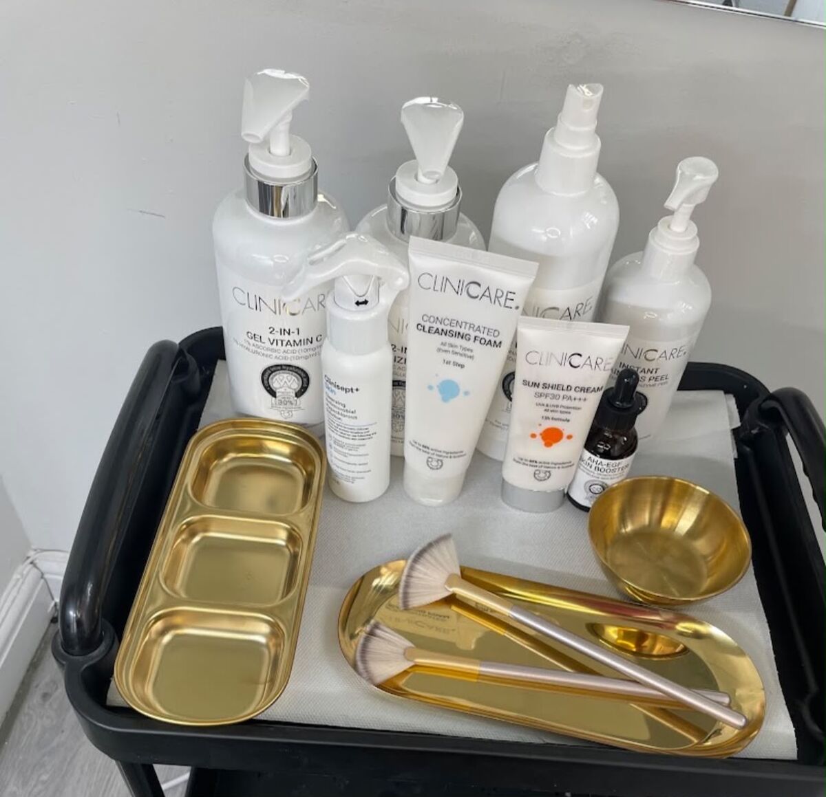 Professional skincare products and gold treatment dishes laid out on the clinic trolley